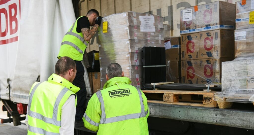 3 workers wearing PPE assessing the best way to handle a pallet in the back of a truck