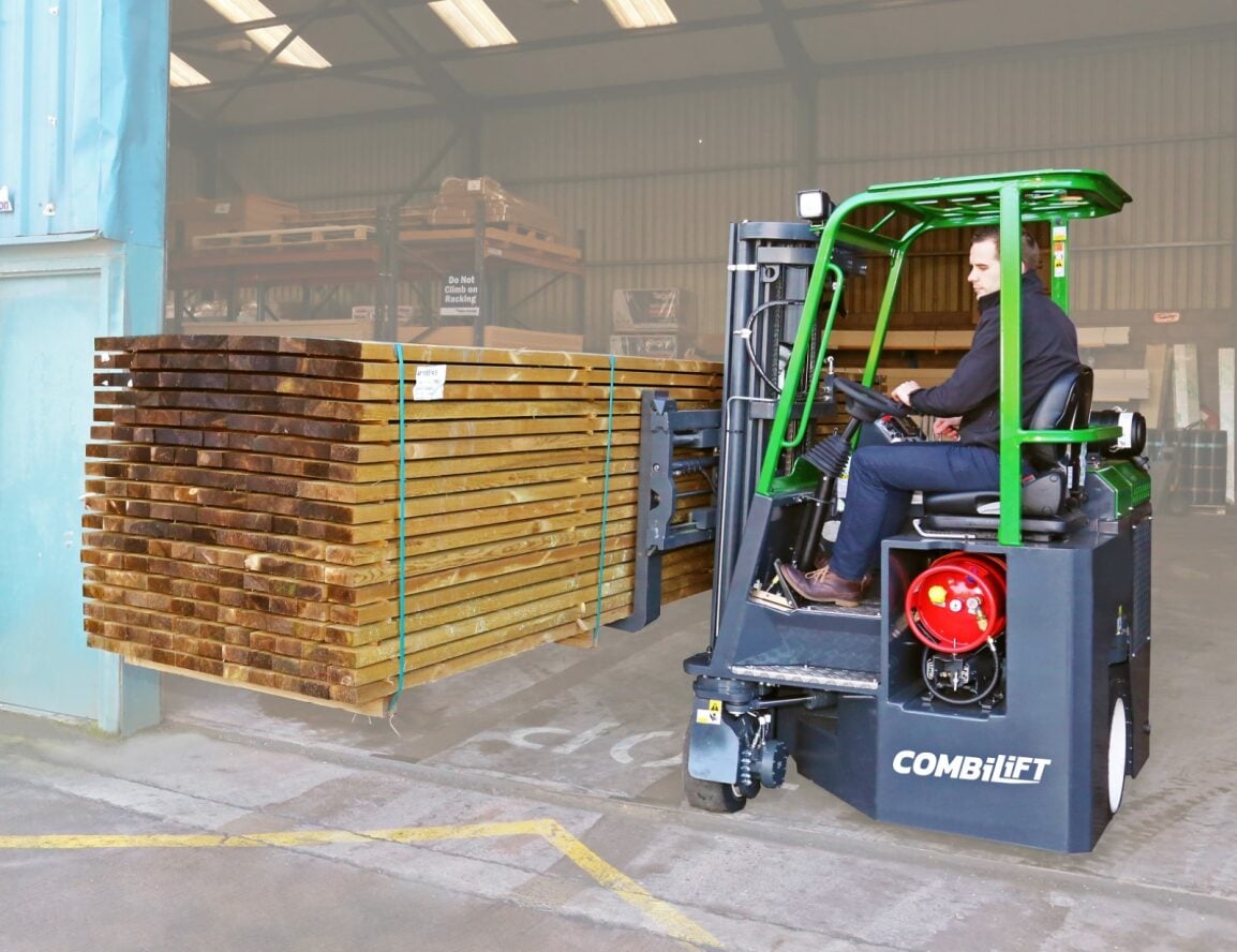 Man operating a gas powered Combilift CB-70E Forklift to move timber in a warehouse environment