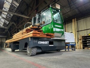 A Combilift sideloader forklift transporting long loads outdoors.