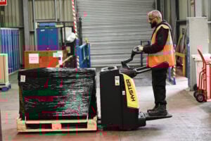 A hyster ride-on pallet truck being used to transport goods within a warehouse.
