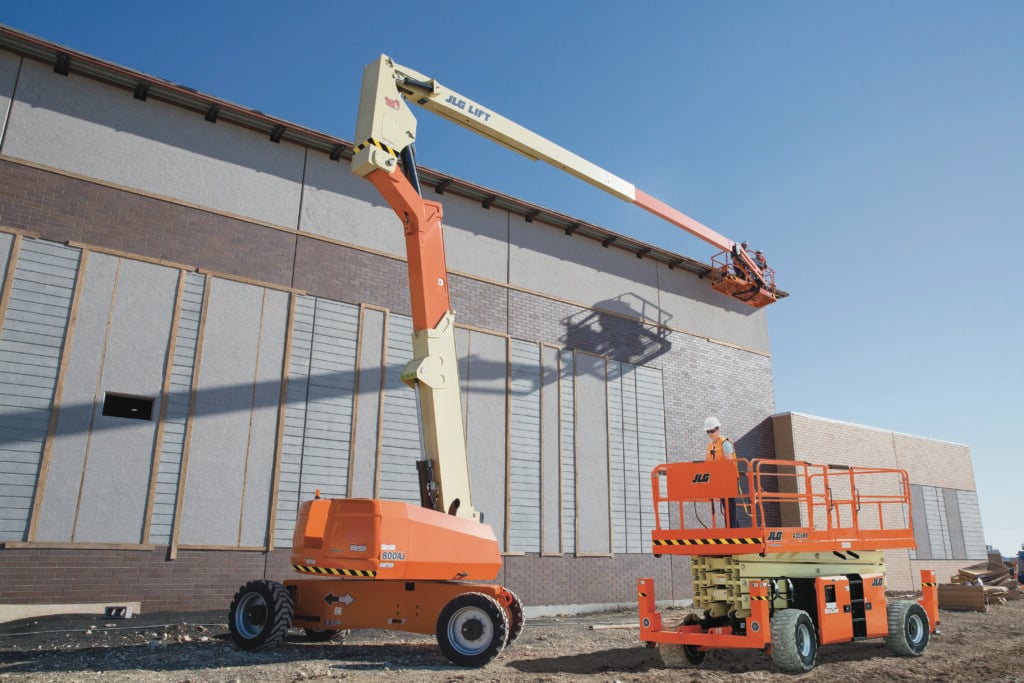 A JLG boom lift and rough terrain scissor lift operating with ease on a construction site.
