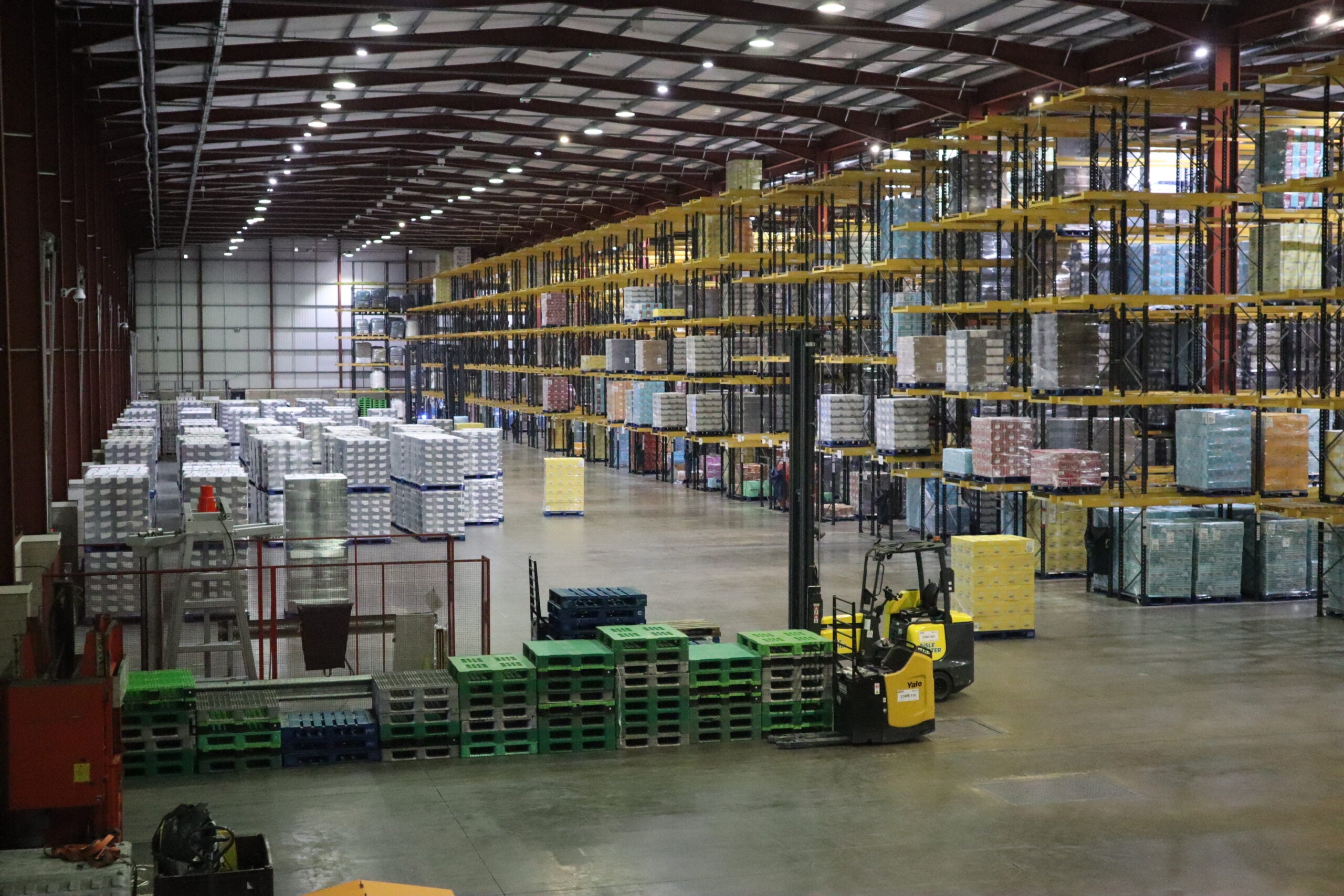 A Combilift Aislemaster and a Yale pallet stacker pictured operating within a warehouse.