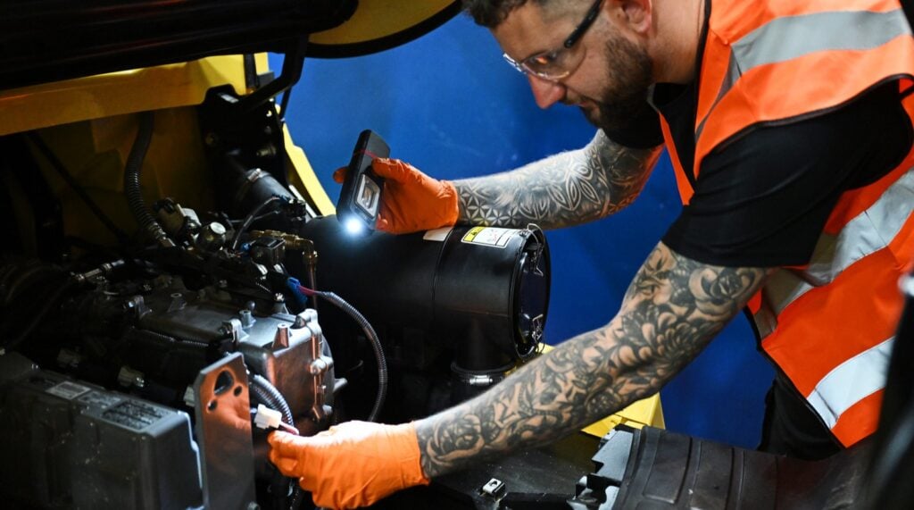 A close up of a Briggs Engineer examining parts of a forklift