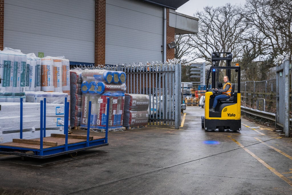 A person driving a Yale reach truck in a yard environment